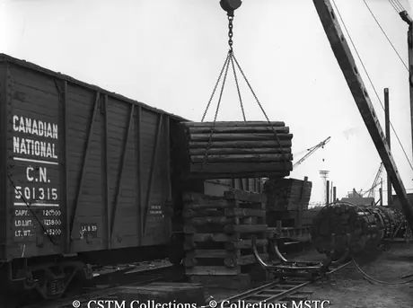 Untreated wood being unloaded from box cars at the Wood Preservation Industries Ltd.