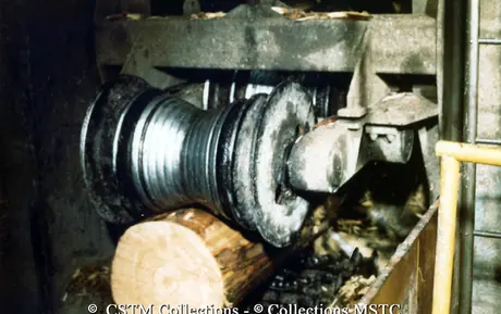 Debarking machine processing a log of wood