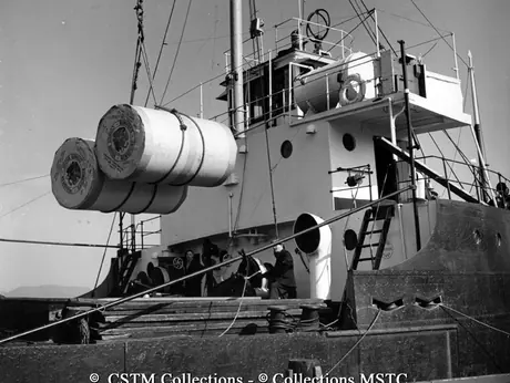 Rolls of newsprint are loaded on board the S.S. Trenora from the dock of Bowater’s Newfoundland Pulp and Paper Mills Limited