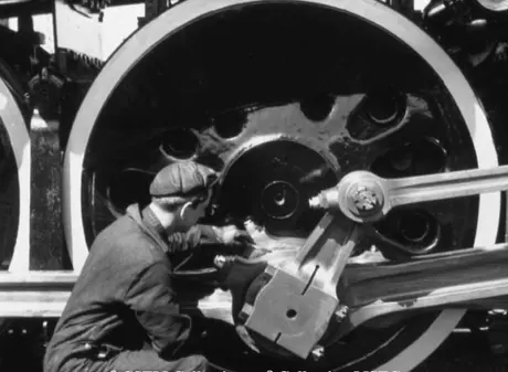A fitter attends to coupling rod and connecting rod bearings on a steam locomotive