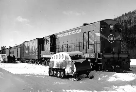 Diesel locomotive 7603 with steam generator car 15613 and a passenger train and snowmobiles