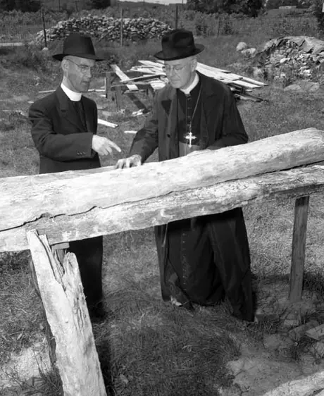 Rev. T.J. Lally, pointing out to Archbishop Beckman the splendid preservation of the 300 year old planks recovered from beneath the foundations of the ancient Fort